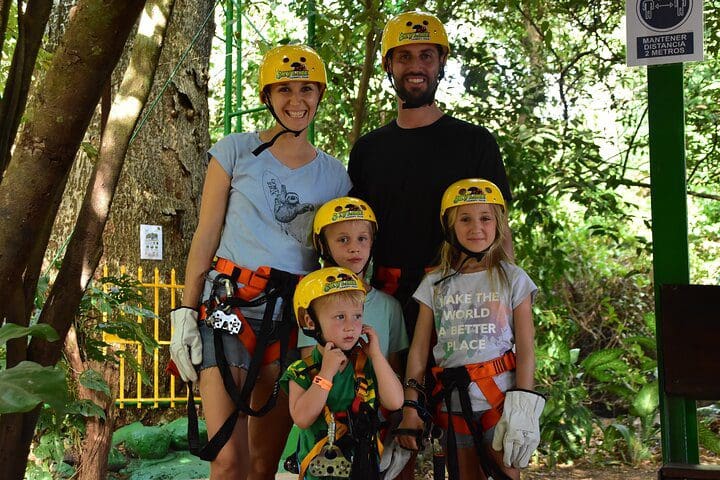 A family of five poses together with their zip-line equipment on during a Skyline Canopy Tour.