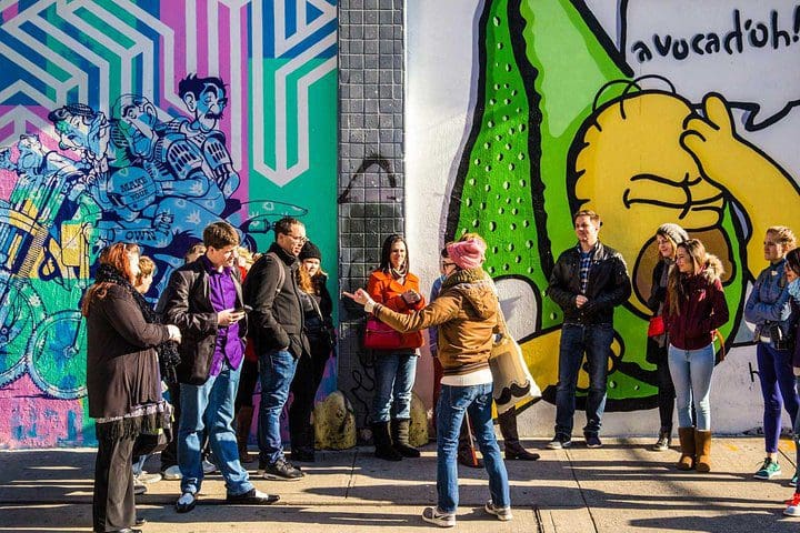 A tour group in front of a street mural, while taking the Soho, Little Italy, and Chinatown Walking Tour In New York.