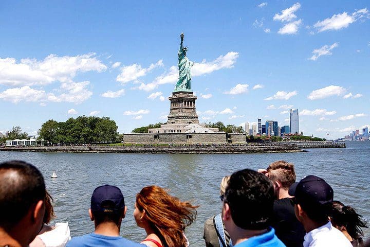 People look on at the Statue of Liberty from a boat on the Statue of Liberty & Ellis Island Tour: All Options.
