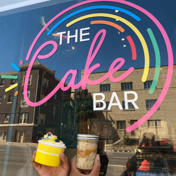 Two ice cream treats in front of the logo for The Cake Bar, one of the best dessert spots in Denver with kids.