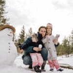 A mom and her young kids build a snowman, while on a Christmas vacation.