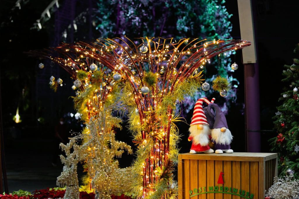 Two gnomes sit on a shelf near Christmas decorations near the Super Trees in Singapore.