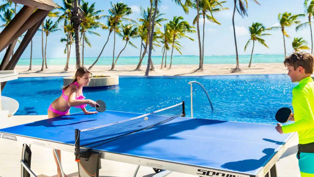 Two children playing ping pong by the pool at the Hyatt Ziva Cap Cana