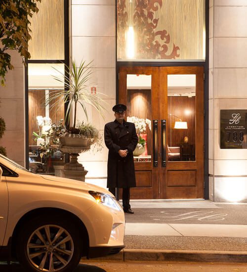 A doorman standing outside L'Hermitage Hotel Vancouver