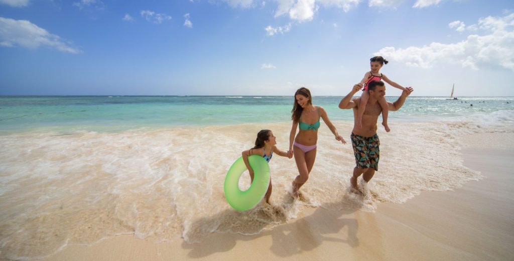 A family running on the beach at the Royalton Bavaro Resort and Spa, one of the best resorts in the Dominican Republic for families.