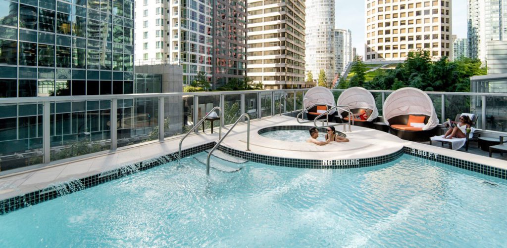 Two guests lounging in the hot tub beside the outdoor pool at the Shangri-La Vancouver, one of the best hotels in Vancouver for families.