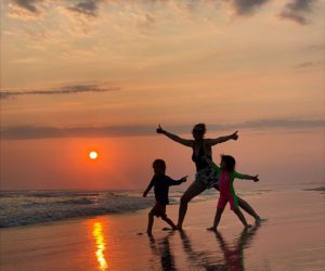 A mother and two children running on the beach during sunset in Oaxaca, Mexico.