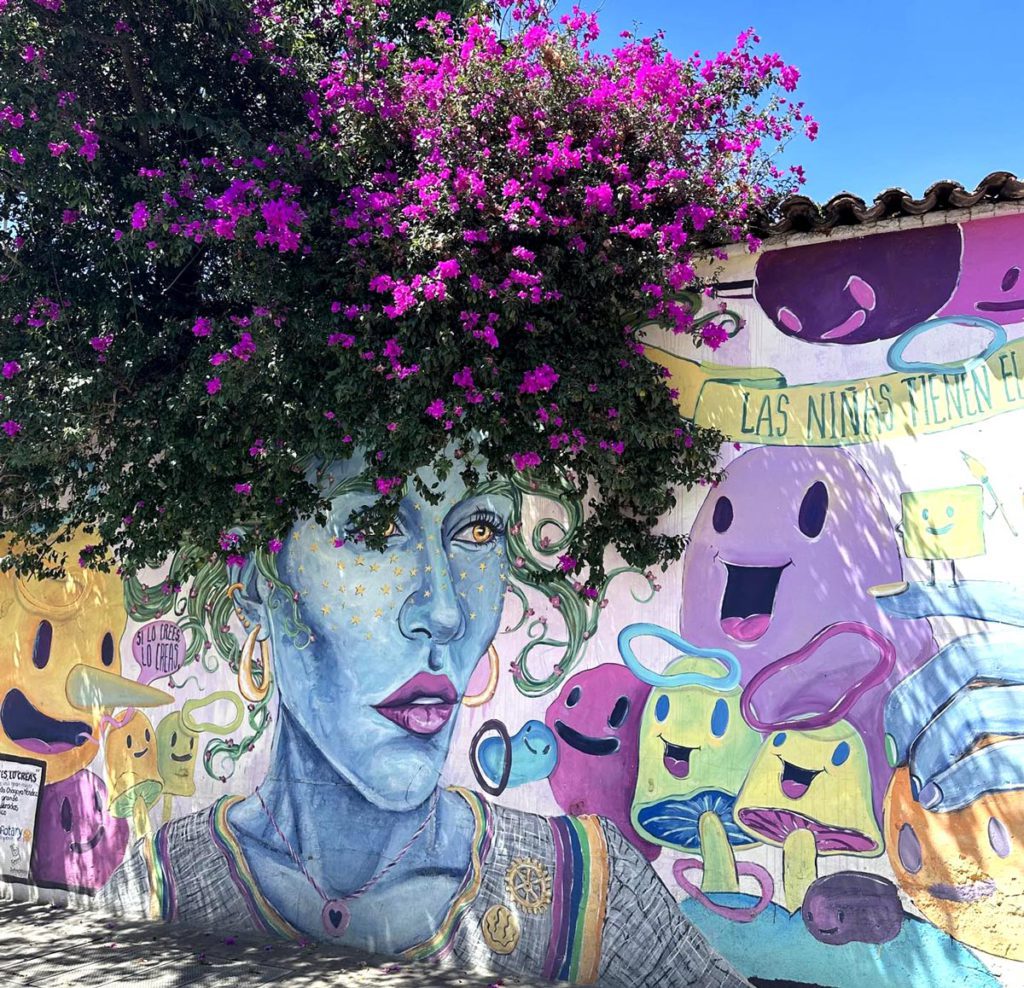 A colorful mural of a woman with cute characters in a small town near Oaxaca.