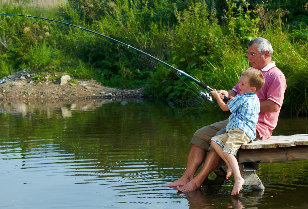 A grandfather and his grandson fishing in South Dakota, one of the best destinations for a family fishing vacation in the Midwest. 