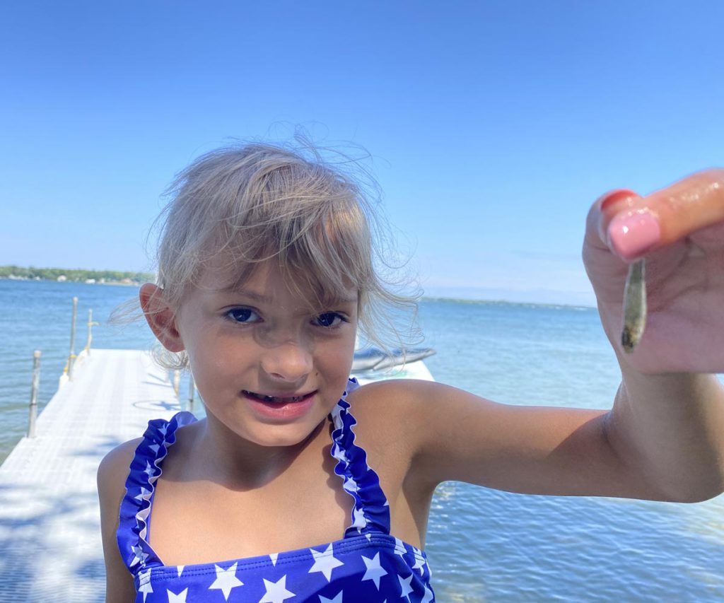 A young girl holding fishing bait during a family fishing vacation in the Midwest. 