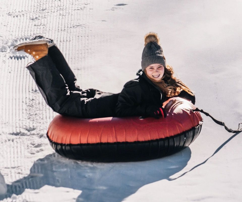 A girl on a red snow tube at Boreal Mountain, one of the best places to go snow tubing in Lake Tahoe with kids.