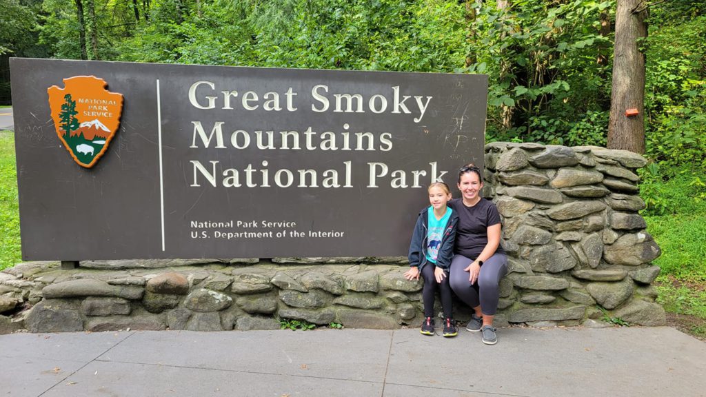 A mom with her child in front of the Great Smoky Mountain National Park Entrance. 