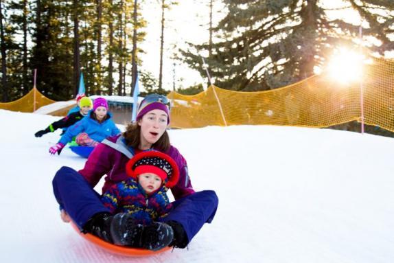 A mother snow tubing with her kids at Tahoe City Winter Sports Park, one of the best places to go snow tubing with kids in Lake Tahoe. 