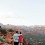 A couple hugging one another while overlooking the red rock in Sedona, one of the best romantic getaways in the United States.