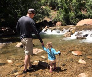 A father and daughter wading through the waters in Zion National Park.