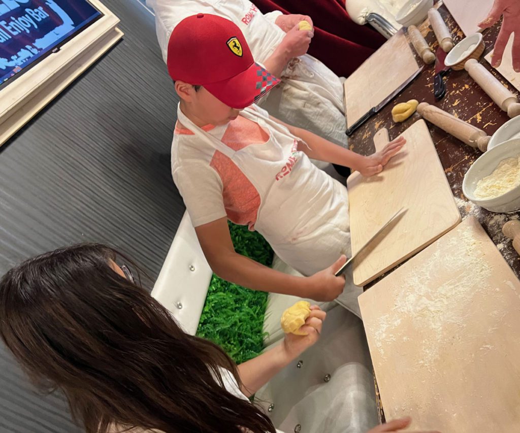 Two kids kneading dough while taking a pasta cooking class in Rome.