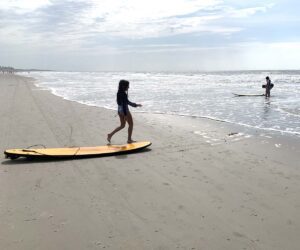 A child on a surfboard on the beach in South Carolina.